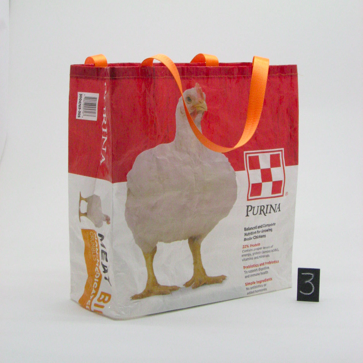 A Purina branded reusable shopping bag with orange handles, featuring a large white chicken graphic on a red and white printed design, photographed against a plain white background.